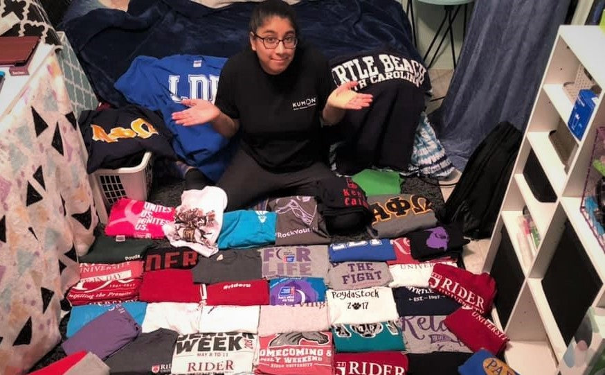 girl sitting with a pile of t-shirts