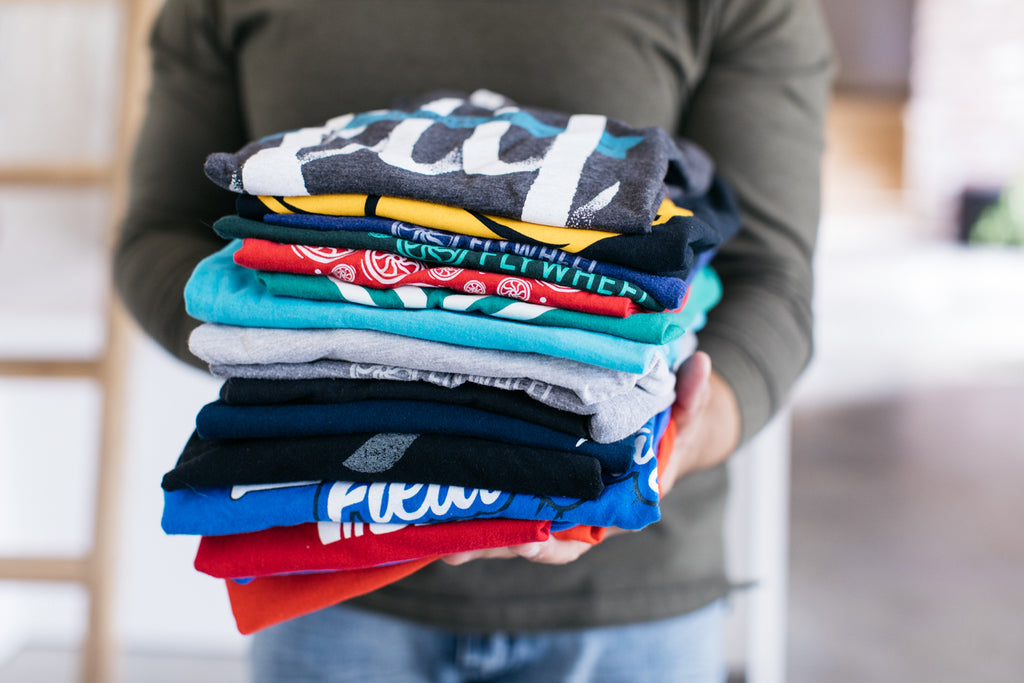 man holding stack of multiple t-shirts