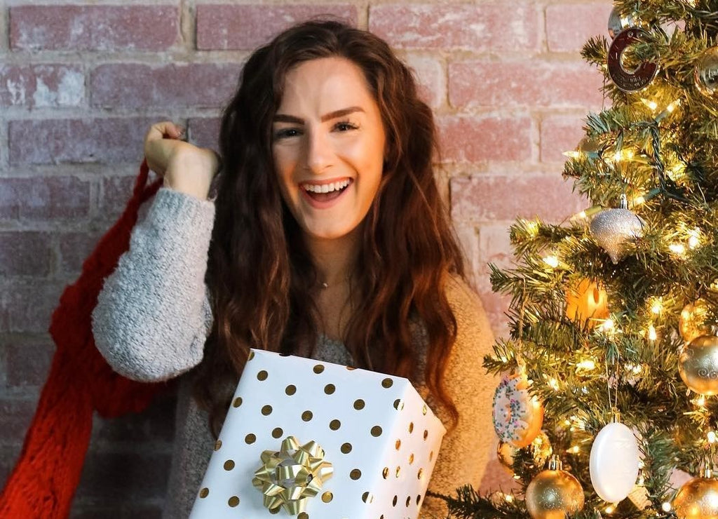 Laughing woman next to Christmas Tree holding Christmas Gifts